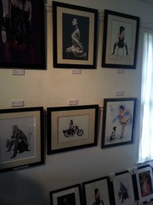 Smaller artworks desplayed on a wall. Two paintings in the upper row are entitled "Silk lady" and "Naughty chair"