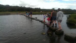 People crossing the Ewenny river using the ancient stepping stones